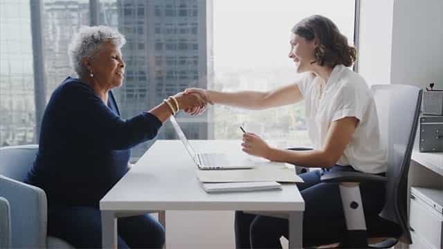 Female financial professional shaking hands with her female client.
